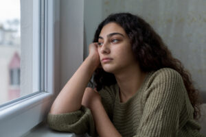 girl looking out window depressed