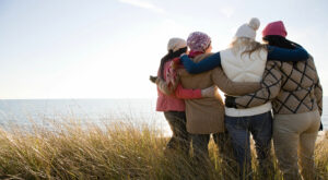 group of women standing facing ocean