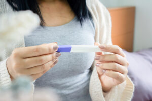 Concerned woman looking at positive pregnancy test